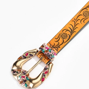 Detail of tan leather belt with floral embossing and gold buckle set with colorful gems