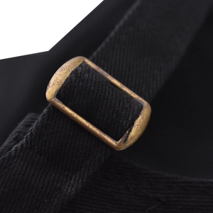 Vista macro della fibbia regolabile in bronzo sul cinturino in twill nero del cappellino