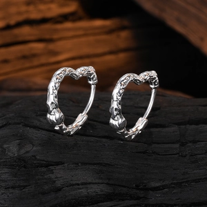 Macro shot of silver heart earrings with irregular texture on dark background