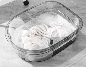 Detail view of thickened transparent plastic laundry tub with soap water and fabric