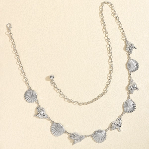 Detail of silver starfish and shell body chain with lobster clasp on beige texture