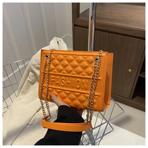 Detail of orange quilted handbag with gold chain and embossed FASHION lettering