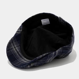 Detail view of the blue plaid newsboy cap interior with lining and wash care label