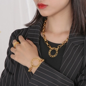 Close-up of gold chunky chain set with Roman numeral engravings on the bracelet and ring