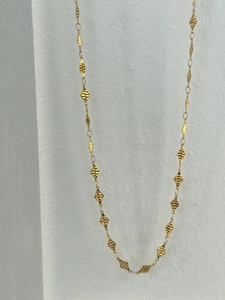 Detailed macro of 18k gold plated waist chain featuring textured diamond-shaped charms