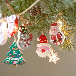 Christmas LED string lights with wooden Santa, snowman and tree ornaments on pine branches