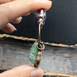 Primer plano detallado de amatista natural y fluorita verde en un colgante de bronce