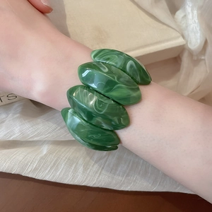 Detail of green marble acrylic stretch bracelet featuring oval resin links on a model's wrist