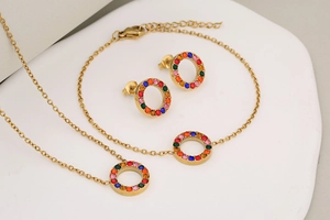 Detail of gold jewelry set with colorful rhinestones on circular pendants and earrings