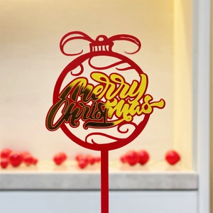 Close-up of a red and gold acrylic Merry Christmas cake topper for holiday party decor
