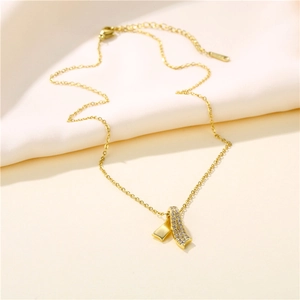 Elegant gold bow pendant necklace with sparkling zircons on a minimalist soft fabric base