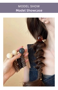 Detail of spiral hair ties with smooth beads in cream, black and amber tones