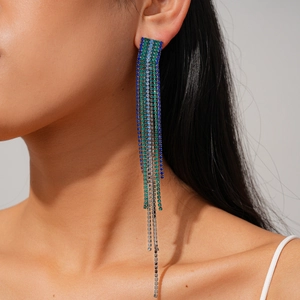 Close-up of long silver fringe earrings with blue and green rhinestones on a female model