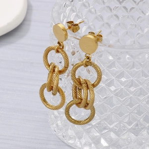 Détail de boucles d'oreilles pendantes dorées avec anneaux en métal texturé