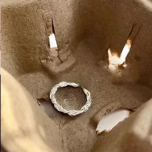 Macro detail of silver braided rope ring with brushed metal texture and open adjustable band