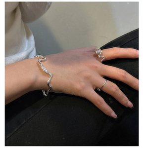 Detail shot of wavy texture silver bangles and rings on wrist for a modern look