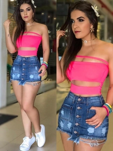Détail du haut court rose fluo pour femme et de la mini-jupe en jean bleu à boutonnage simple