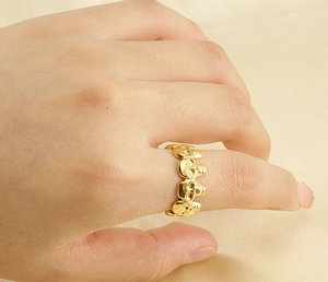 Close-up of golden punk skull ring worn on index finger with unique multi-skull design