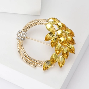 Macro detail of elegant golden leaf brooch with yellow crystals and sparkling rhinestones