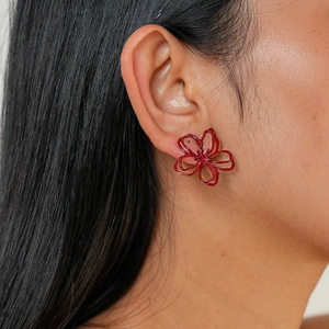 Gros plan de boucles d'oreilles fleurs rouges évidées pour un style rétro chic et élégant