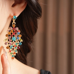 Detail of vintage gold earrings with colorful round gemstones on model, retro palace style