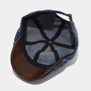 Internal view of denim newsboy cap with black cotton straps and orange contrast stitching