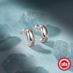 Poliertes S925 Sterlingsilber C-Form Creolen auf blauem Kristallstein Hintergrund