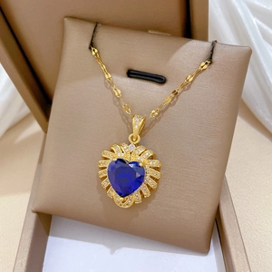 Macro shot of gold-plated heart pendant with deep blue gemstone and pavé zircon details