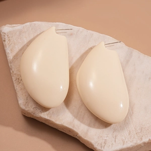 Détails de boucles d'oreilles géométriques en résine crème sur un support en pierre