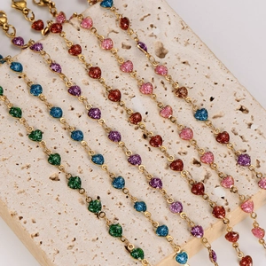 Colorful glitter heart charms on gold stainless steel bracelets over travertine background