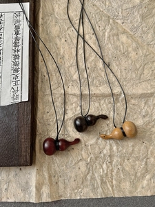 Détails de trois pendentifs en forme de gourde en bois faits main aux couleurs naturelles