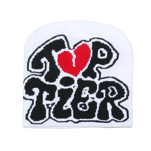 Détail du bonnet blanc en tricot avec lettrage noir TOP TIER et motif jacquard cœur rouge