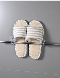 Detail of adhesive wall hooks and stainless steel rod holding striped slippers
