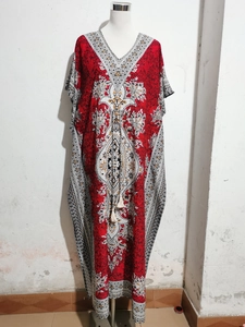 Detail of red bohemian kaftan with V-neck, tassels, and intricate mandala print patterns