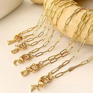 Detailed view of gold rectangle link chains with sparkling crystal letter pendants