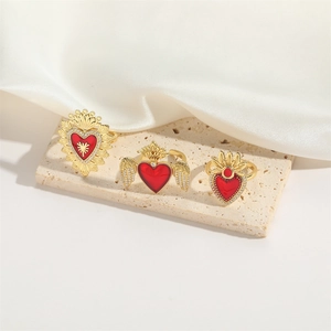 Elegant gold heart rings with wings and crown charms on beige stone and silk