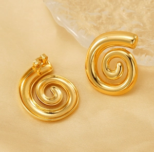 Dettaglio macro di orecchini a spirale in acciaio placcato oro 18k su seta pregiata