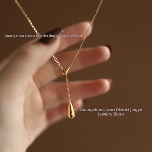 Macro detail of gold Y-shaped necklace featuring dual teardrop pendants on fine chains