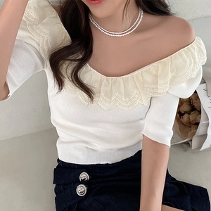 Close-up of off-white knitted off-shoulder top with elegant ruffle lace detailing