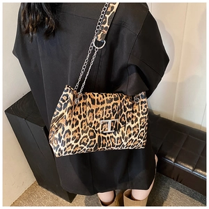 Model wearing leopard print shoulder bag with metal chain strap and silver T-clasp