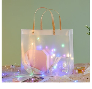 Close-up of frosted semi-transparent PVC gift bag with rivet-fixed handles and LED lights