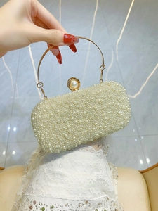Dettaglio della pochette da sera perlata con manico tondo dorato e texture perla avorio