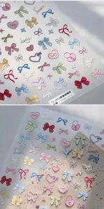 Macro detail of 3D embossed sweet bow and heart nail art stickers in pastel colors