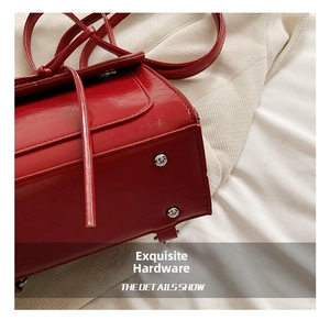 Detail shot of bright red glossy tote bag base featuring silver metal protective studs