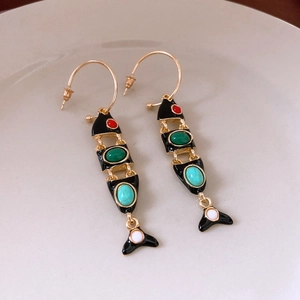 Detailed close-up of vintage fish tassel earrings with colorful beads on ceramic tray