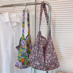 Detail of vintage floral print cotton tote bags hanging on a rack in a bright room