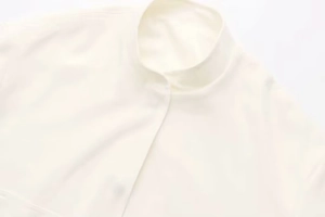 Gros plan sur une veste blanche minimaliste avec col montant et texture tissée fine