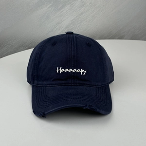 Detailed macro view of distressed navy baseball cap with white Haaaaapy letter embroidery