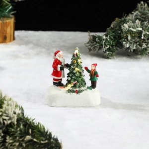 Macro detail of glowing resin Christmas house featuring Santa Claus and a lighted tree