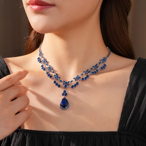 Close-up of teardrop blue crystal pendant necklace on model with elegant silver setting